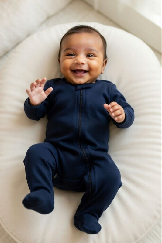 Baby in a navy blue onesie lying on a white cushion
